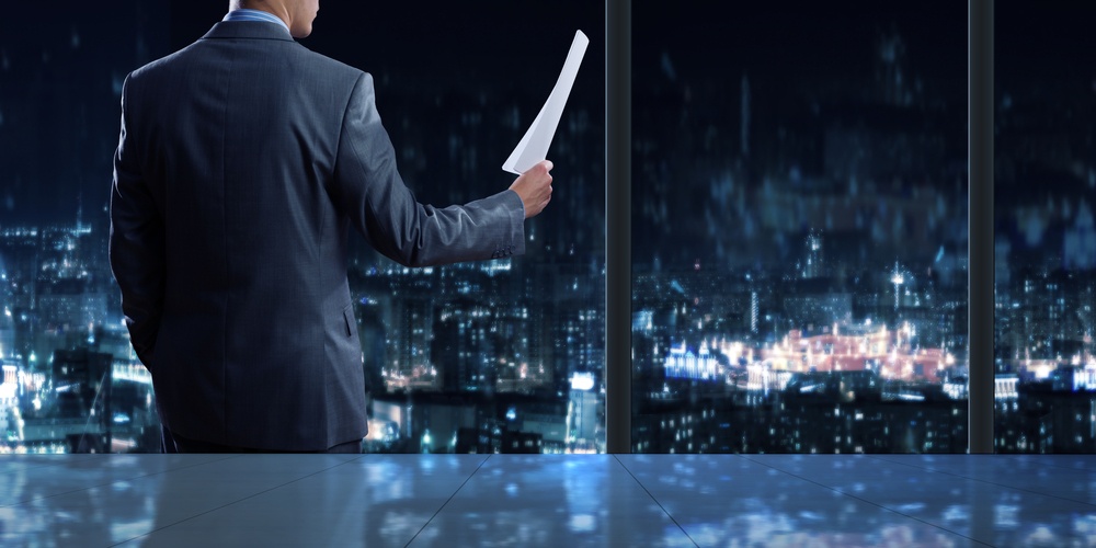 Businessman standing against office window reading documents