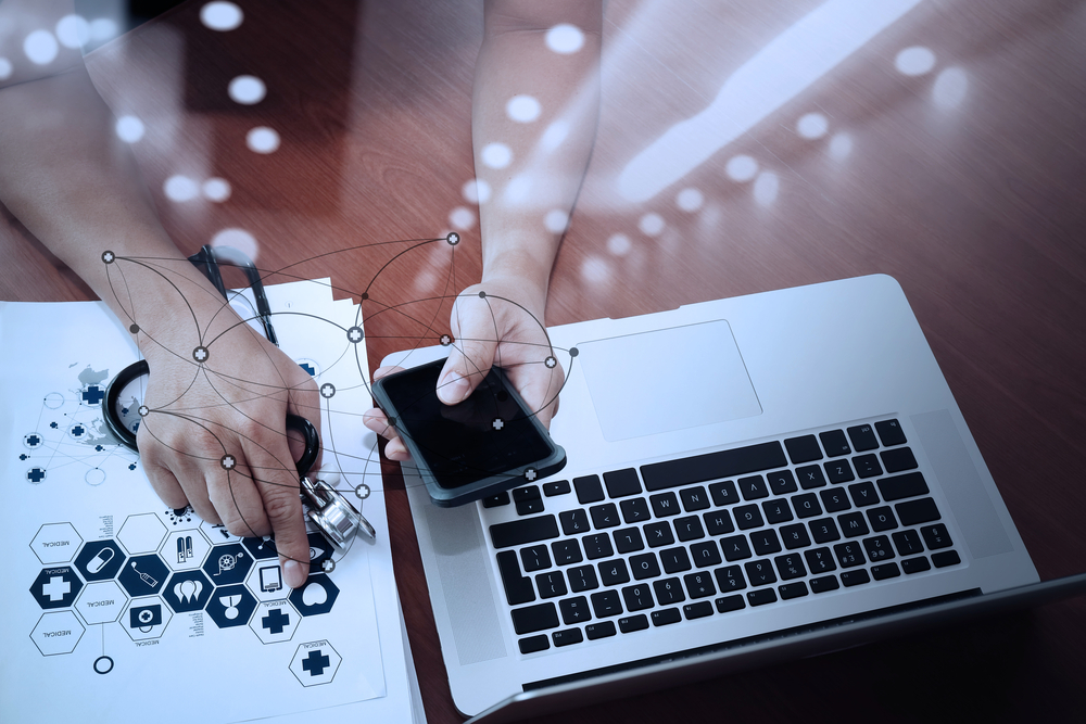 top view of Medicine doctor hand working with modern computer and smart phone with social media network on wooden desk as medical concept top view of Medicine doctor hand working with modern computer and smart phone with social media network on wooden desk as medical concept